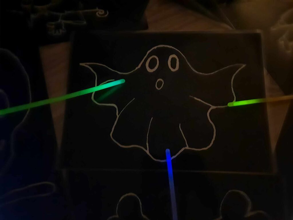 duch na ciemnym tle ze świecącymi patyczkami fluorescencyjnymi - fiszki na halloween DIY